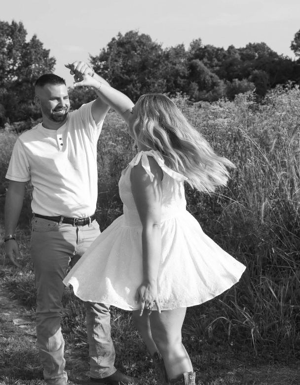 A bride and groom dancing in a sunlit summer field, in black and white